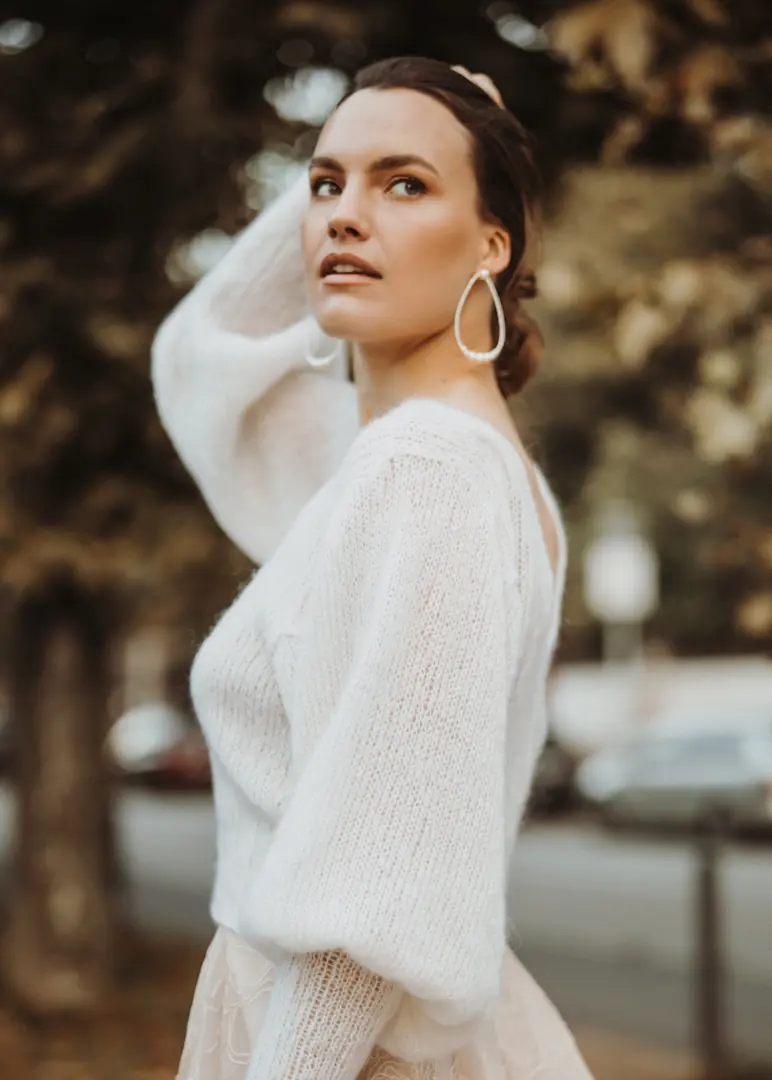 Eine Braut trägt einen weißen, locker gestrickten Pullover im Freien.